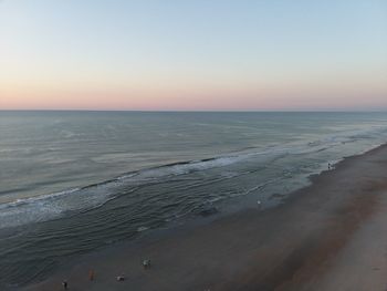 Scenic view of beach against clear sky during sunset