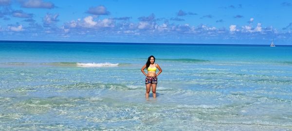 Rear view of woman standing at beach against sky