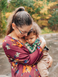 Mother out on a lovely fall or autumn day embracing her son