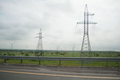 Electricity pylon on road against sky