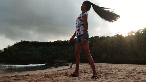 Full length of woman standing on beach against sky