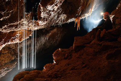 Mature man with illuminated headlamp in cave