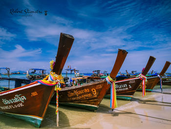 Fishing boats moored at harbor against blue sky