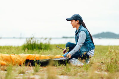 Side view of young woman sitting on field