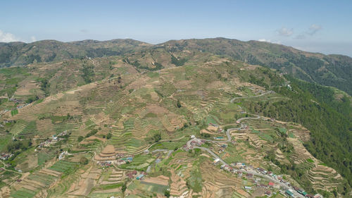Aerial view of rice terraces and agricultural farm land on the slopes of mountains valley. 