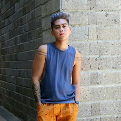 Portrait of young man standing against wall