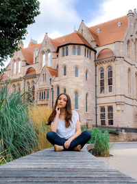 Portrait of woman sitting against building