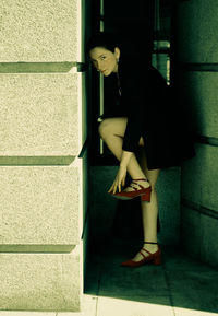 Portrait of woman standing on tiled floor amidst wall