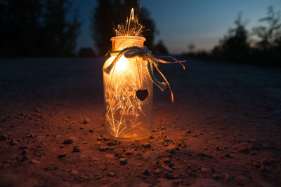 Close-up of illuminated electric light against sky at night