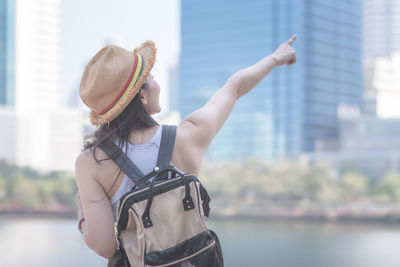 Midsection of woman wearing hat standing against city in background