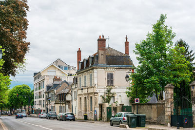 Cars on road by buildings against sky