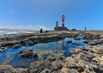 Lighthouse by sea against sky