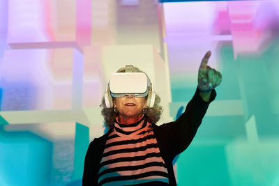 Elderly female in vr glasses and headphones exploring cyberspace