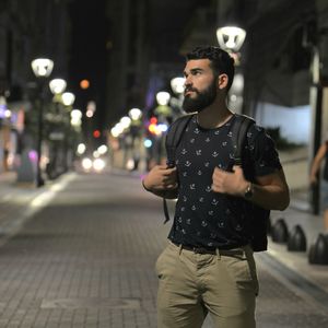Young man looking away in city at night