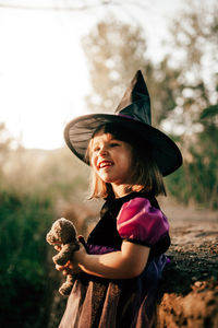 Girl wearing hat standing against plants