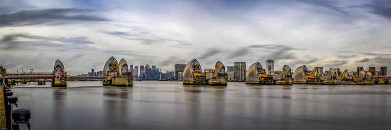 Panoramic view of buildings by river against cloudy sky