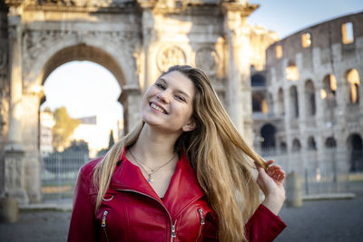 Young woman traveling to rome.  woman takes a picture of herself in front of the arch of titus.