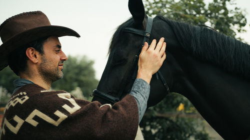 Side view of man wearing hat against sky