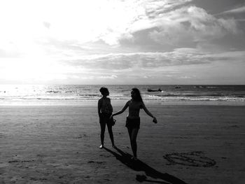 Children playing on beach against sky