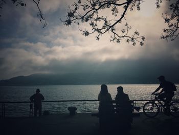 Silhouette people by sea against sky