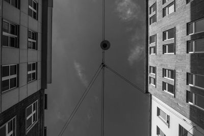 Directly below shot of cables amidst buildings against sky