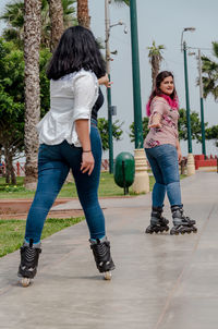 Full length rear view of women standing against plants