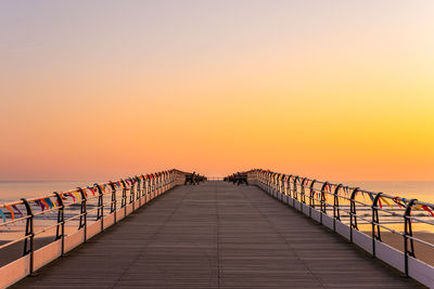 Footpath by sea against orange sky