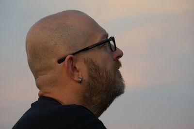 Close-up of thoughtful mature man looking away against sky during sunset