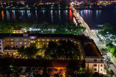 Illuminated buildings by lake in city at night