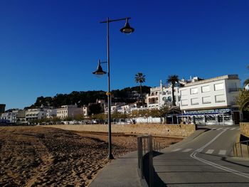 Street by buildings against clear blue sky