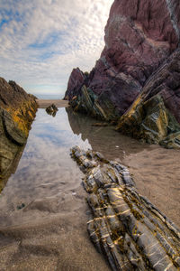 Rock formation on sea shore against sky