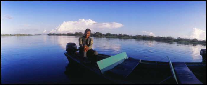 Men sitting on boat in lake against sky