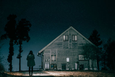 Rear view of person against house at night