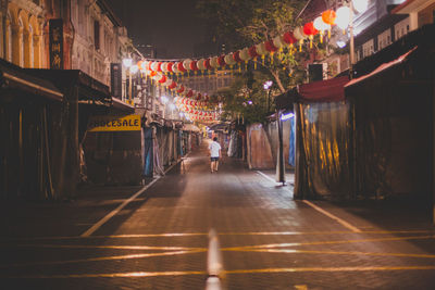 Illuminated road amidst buildings in city at night