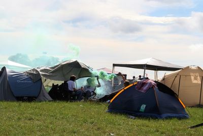 Tents on field against cloudy sky