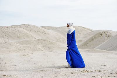 Woman standing on sand in desert against sky