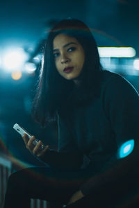 Young woman using phone at night