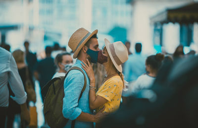 Side view of man holding woman standing in city