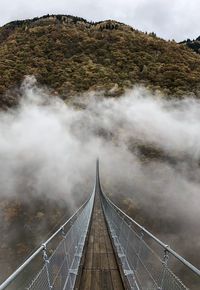 Tibetan footbridge over mountain against sky and foog