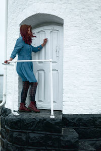 Side view of woman standing against door