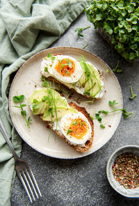 Bread toast, boiled eggs, avocado slice, microgreens on a plate, breakfast time