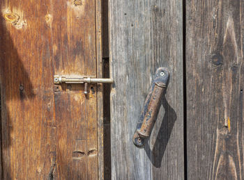 A fragment of an old wooden door with a rusty bolt and handle.