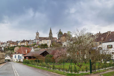 Road by buildings in town against sky