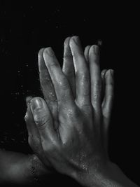 Close-up of wet hand against black background