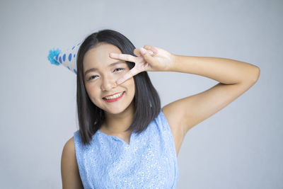 Portrait of a smiling young woman against gray background