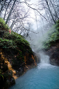 Scenic view of waterfall in forest against sky