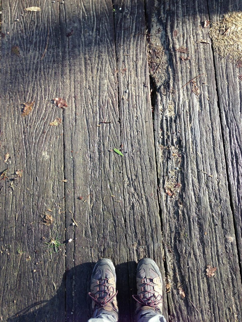 low section, person, shoe, personal perspective, standing, wood - material, human foot, footwear, lifestyles, wooden, high angle view, men, unrecognizable person, boardwalk, jeans, leisure activity, plank