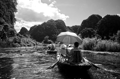 People in boat on river against sky