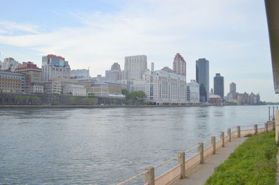 River by buildings in city against sky