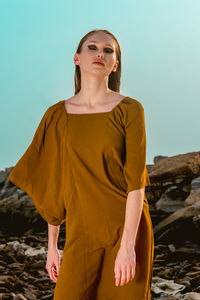 Portrait of young woman standing against clear sky